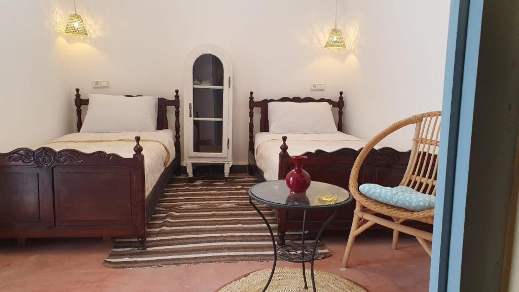 马拉喀什Dar Malwan的一间卧室配有两张床、一张桌子和一把椅子