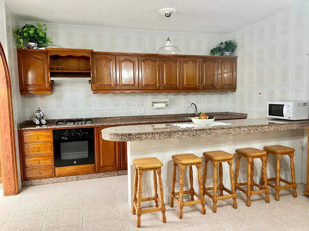 蓬塔穆赫雷斯Casa Los Jameos的厨房配有木制橱柜和带酒吧凳的台面。