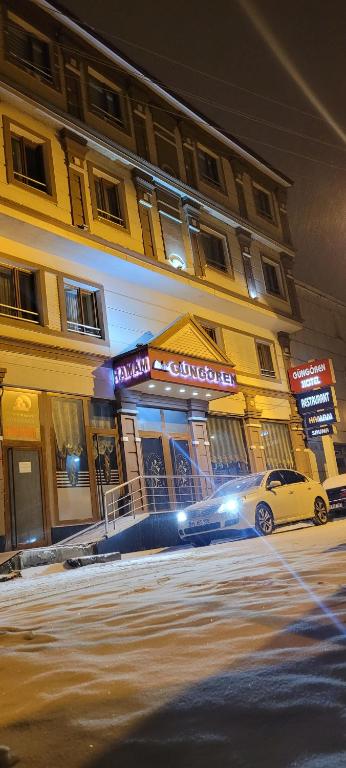 卡尔斯Güngören Hotel的夜间停在大楼前的汽车