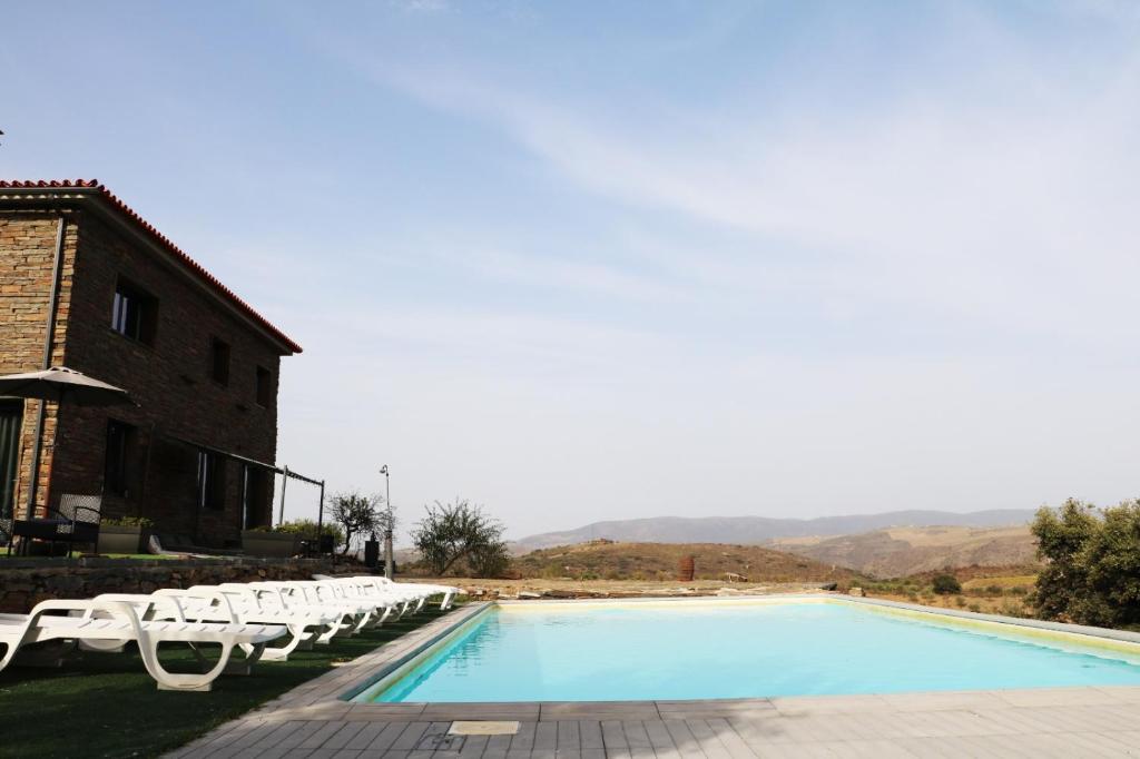 福什科阿新镇Eira da Fraga的一座带白色躺椅的游泳池,位于大楼旁