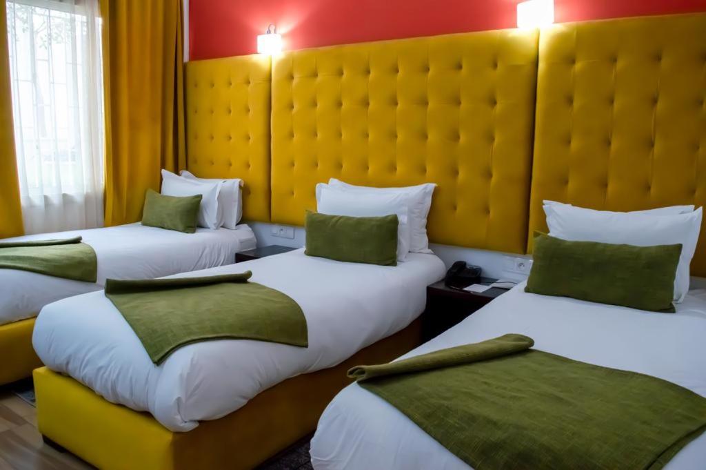 拉巴特博物馆酒店的酒店客房,配有3张带绿色枕头的床