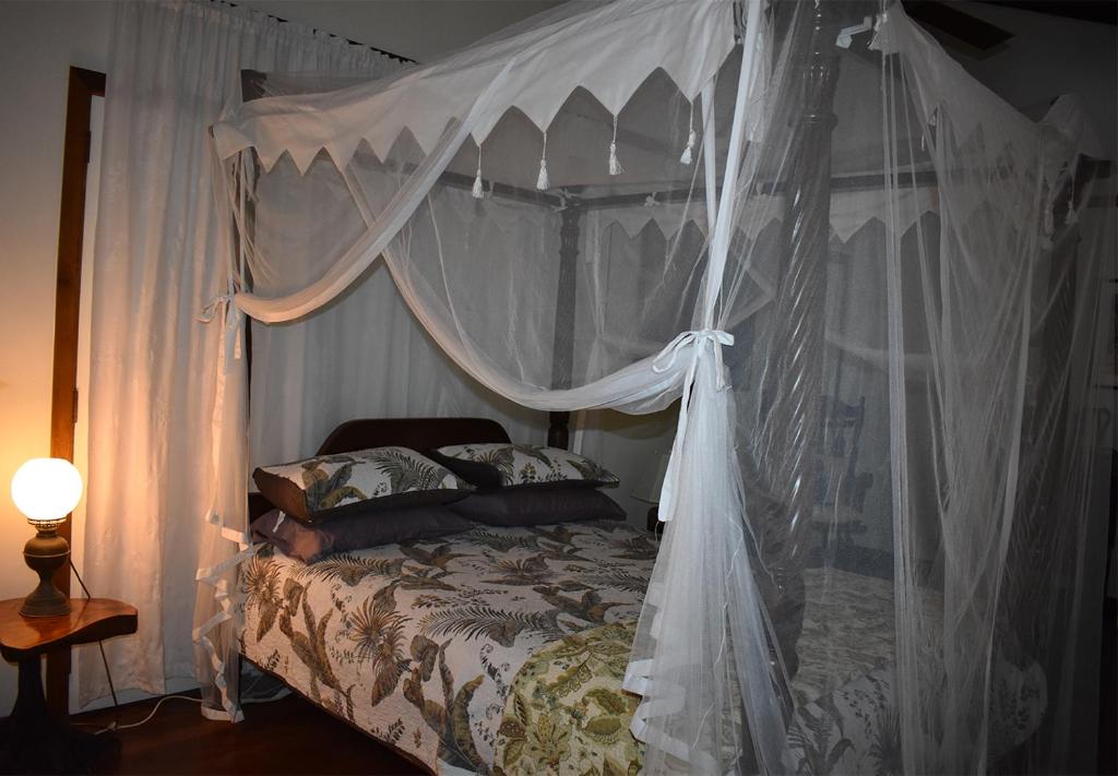 耐莉湾奥斯卡尔雨林住宿加早餐旅馆的卧室配有带白色窗帘的天蓬床