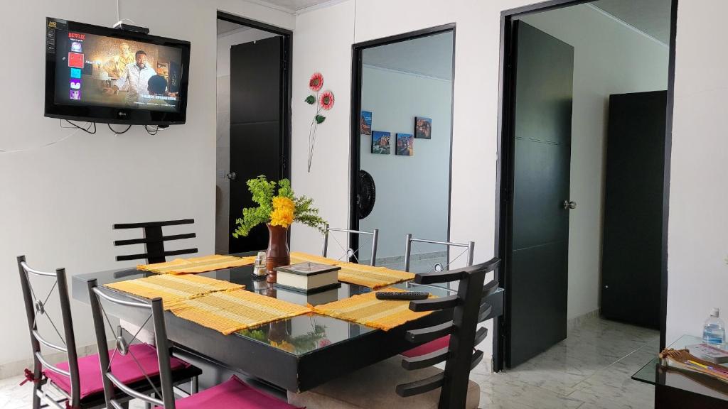 比亚维森西奥Apartamentos El Caudal, Villavicencio的一间设有桌子和墙上电视的用餐室