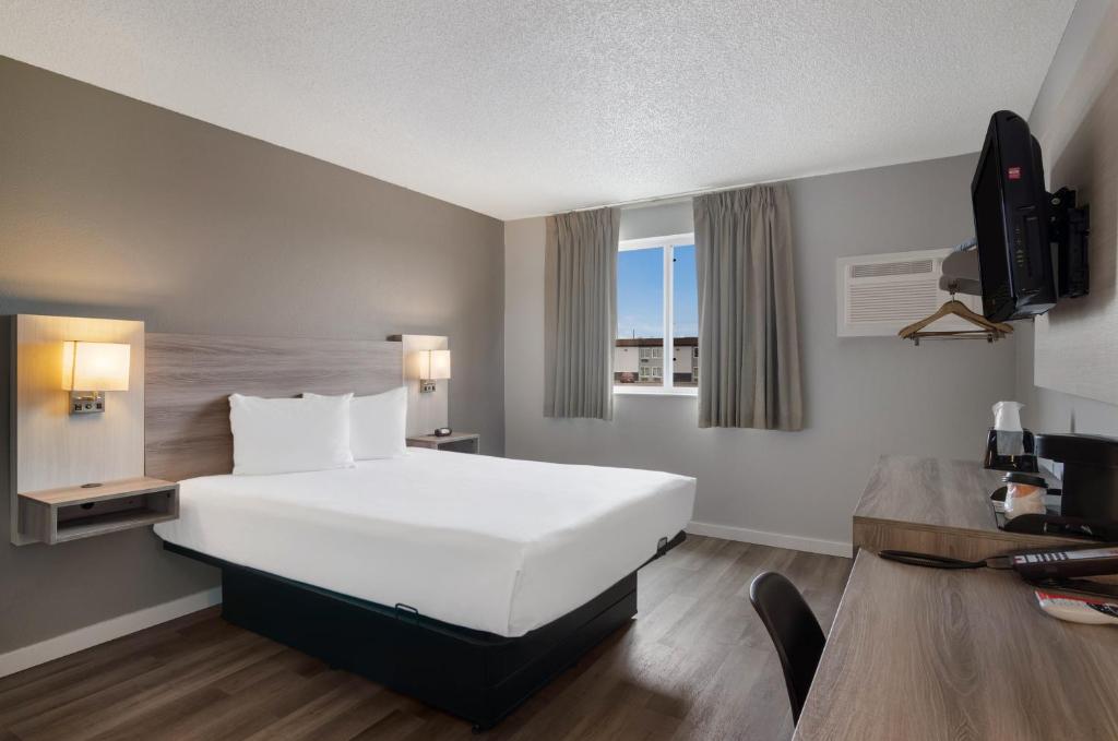 斯科茨布拉夫Econo Lodge Scottsbluff的酒店客房设有一张白色大床和一张书桌