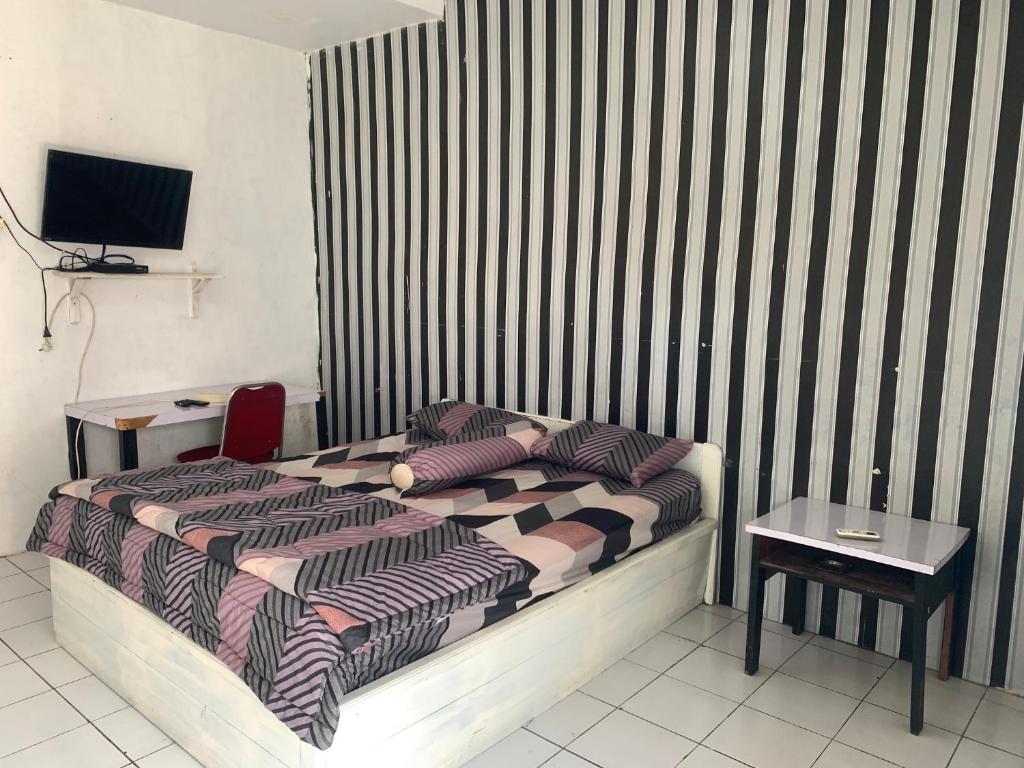 庞卡兰布翁ASOKA GUEST HOUSE的一间卧室配有一张床、一张桌子和一台电视。
