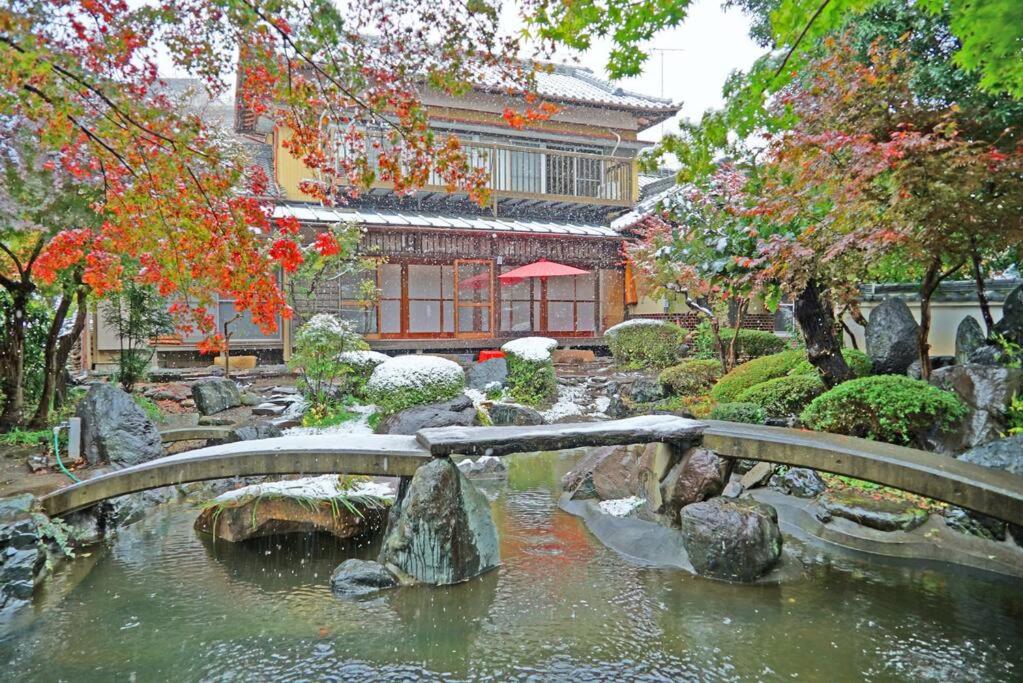横滨日本庭園古民家　飯田屋　Traditional experience iidayajapan的一座桥在一座建筑前面的池塘上
