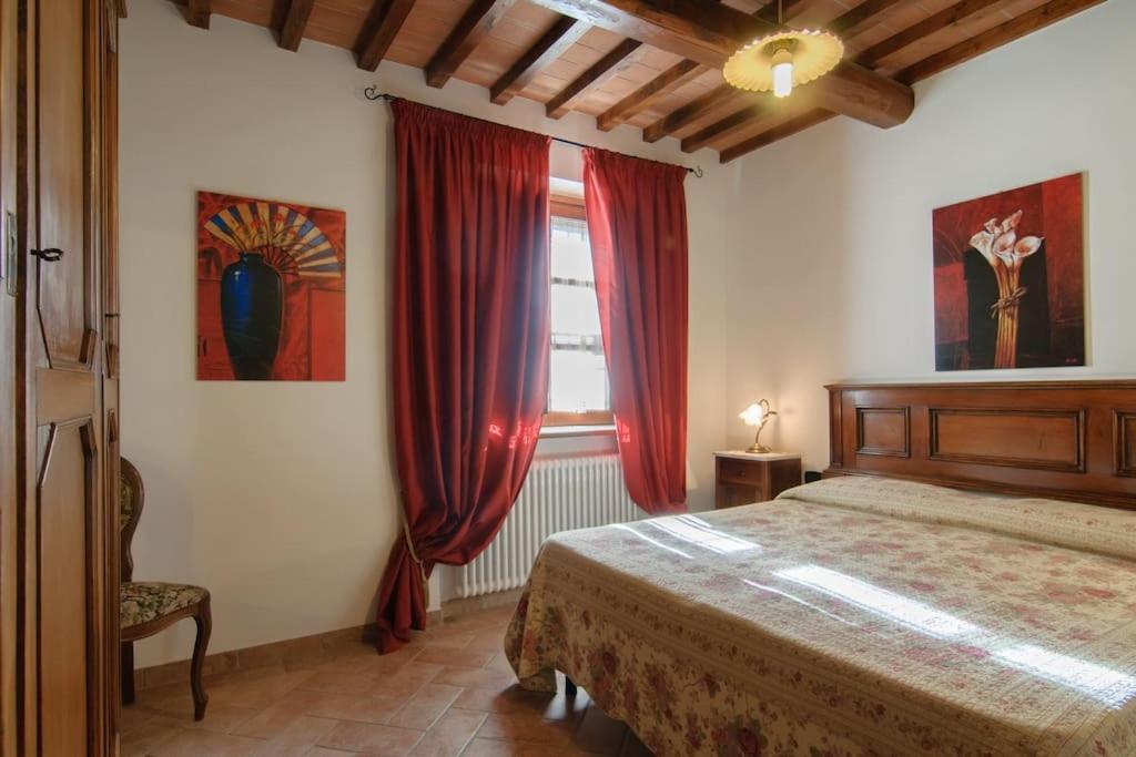 特拉西梅诺湖畔托罗帕鲁金尼乡村民宿的一间卧室配有床和红色窗帘的窗户