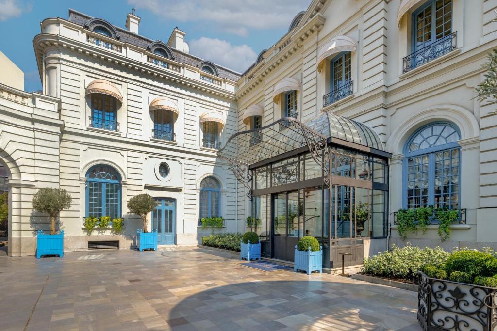 马德里Santo Mauro, a Luxury Collection Hotel, Madrid的一座白色的大建筑,庭院里种有盆栽植物