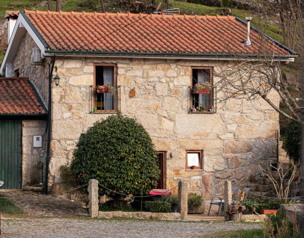 蒙丁-迪巴什图Casa Senhor da Ponte的一座石头房子,设有两扇窗户和屋顶