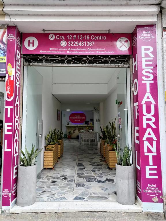 弗洛伦西亚Hotel Amazon的粉红色的入口,通往带桌椅的建筑
