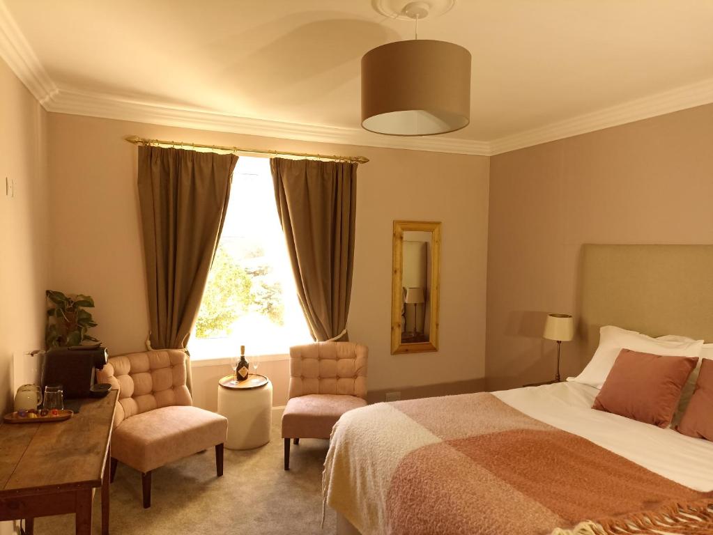 达夫敦Abbeyfield B&B的一间卧室配有一张床、两把椅子和一个窗户
