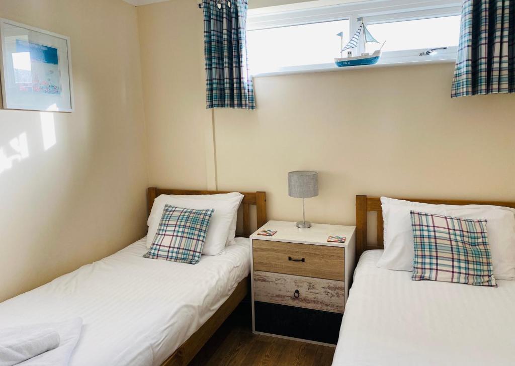 佩伦波斯Dunes View - Atlantic Bay的小型客房设有两张单人床和床头柜。