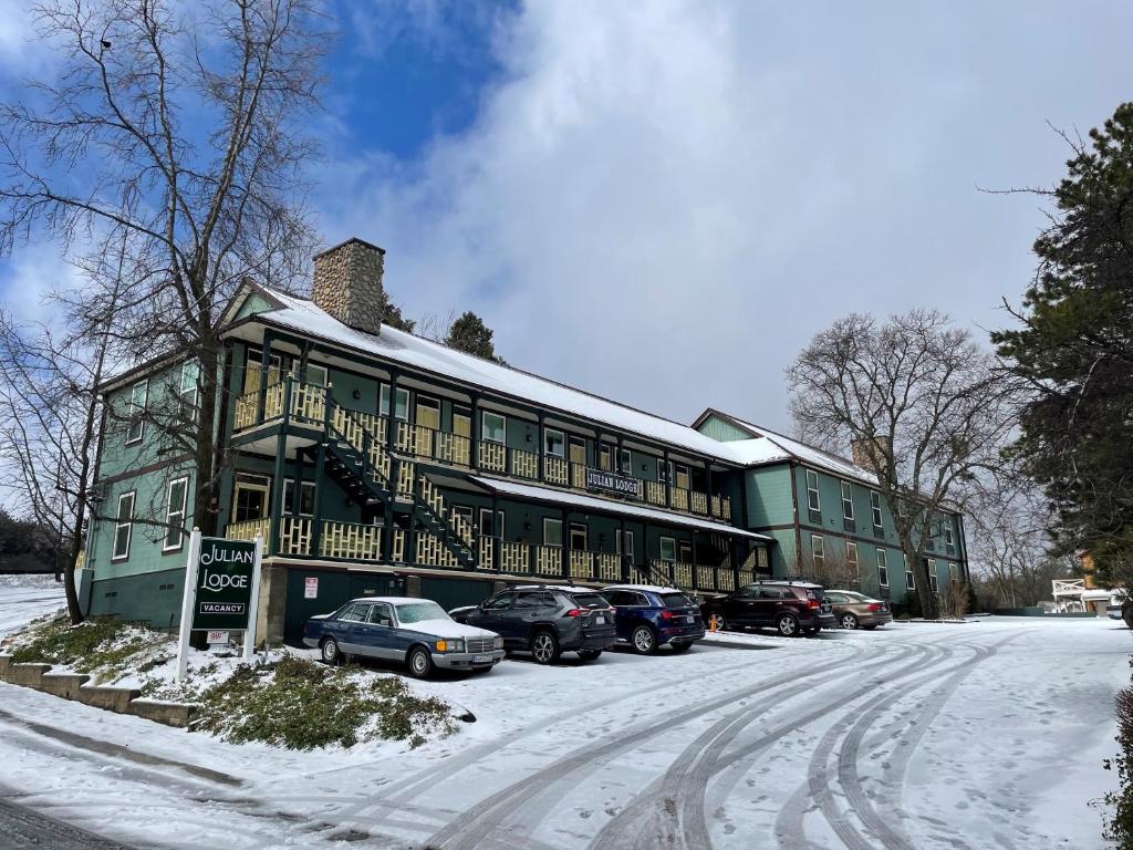 朱利安Julian Lodge的一座绿色的建筑,里面装有汽车停在雪上