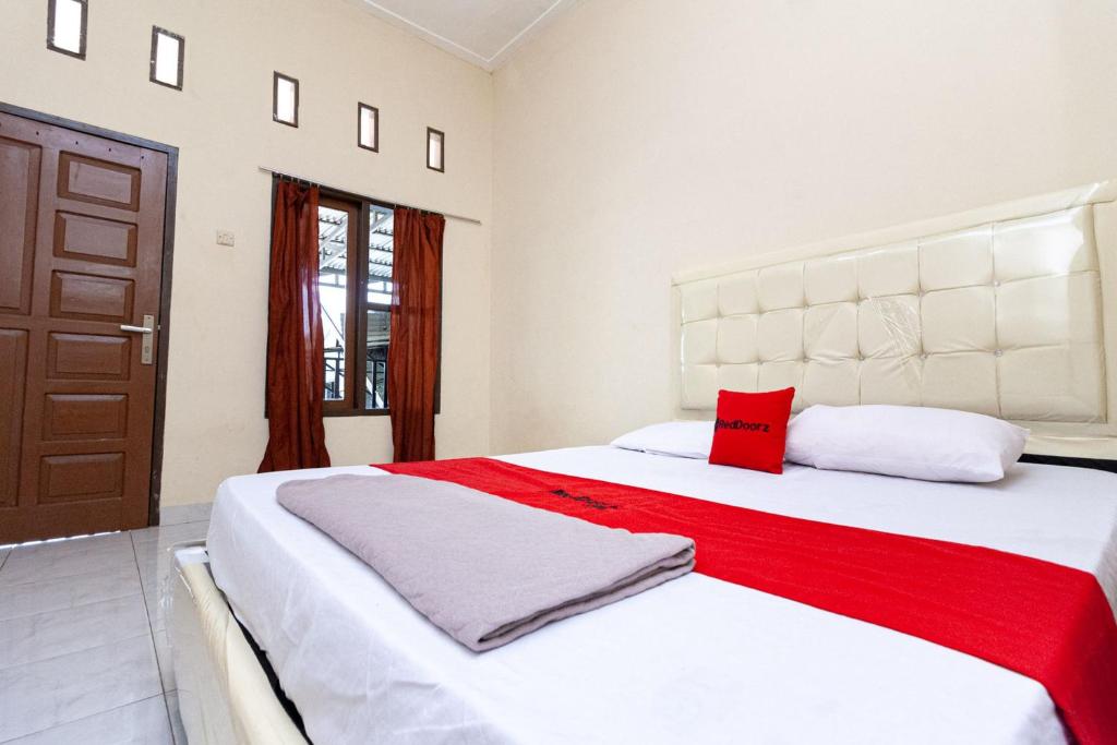 占碑市RedDoorz @ Jalan Sidomuncul 2 Jambi的卧室配有一张大白色床和红色枕头