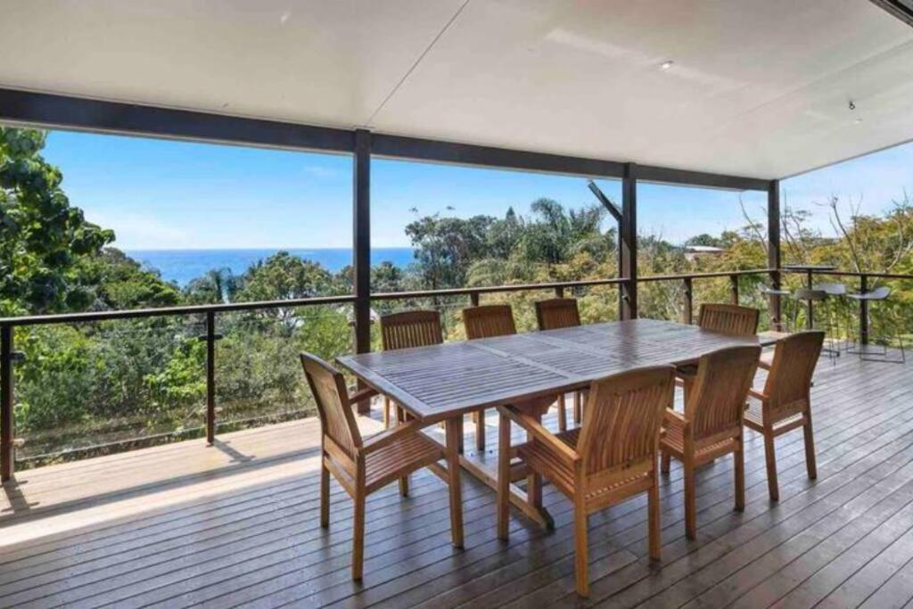 波因特卢考特Treetops on Tramican - Ocean View - sleeps 10的美景甲板上的餐桌和椅子