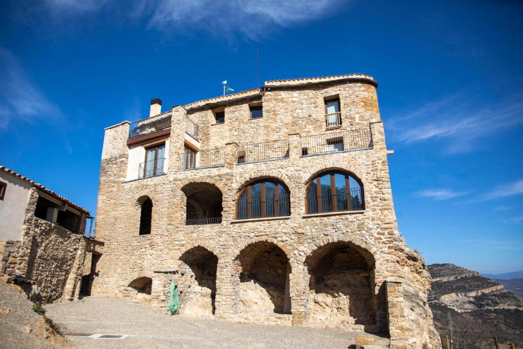 EstormCasa Sanui. Apartaments turístics rurals的一座带窗户的大型石头建筑,位于山上