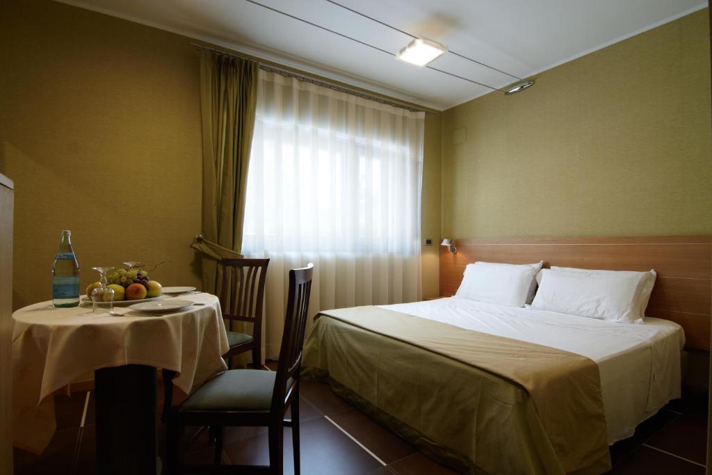 圣乔瓦尼·罗通多Hotel Villa San Pietro的一间卧室配有一张床、一张桌子和一个窗户。