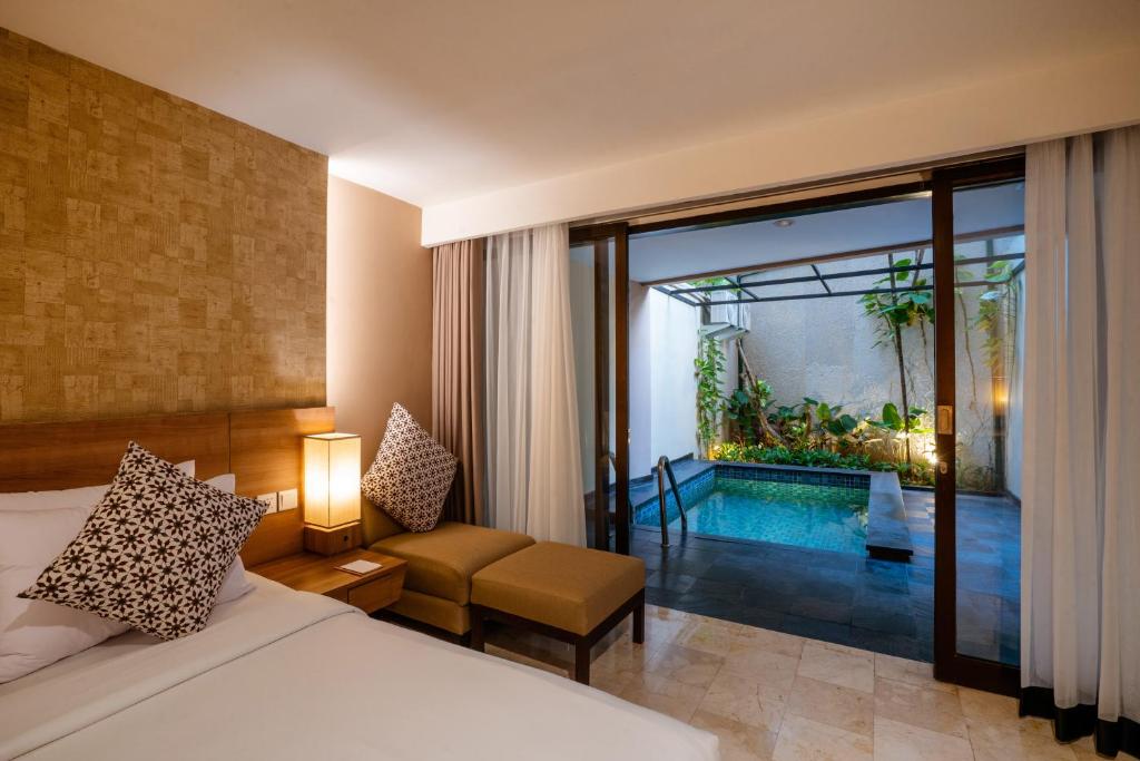 库塔Cross Vibe Paasha Atelier Bali Kuta的一间卧室设有一张床,另一间卧室设有游泳池
