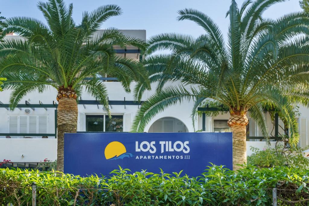 帕格拉Apartamentos Los Tilos的棕榈树建筑前的标志