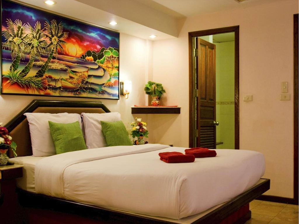 卡伦海滩天堂客栈的卧室配有一张白色大床,墙上挂有绘画作品