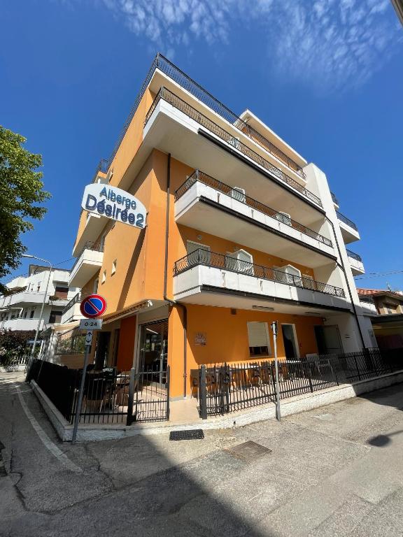 阿尔巴·阿德里亚蒂卡Albergo Désirée 2的一座橙色的建筑,旁边标有标志