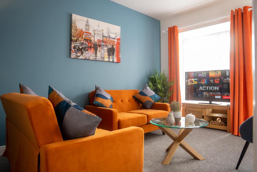 米尔顿凯恩斯Comfortable 4 Bedroom Home in Milton Keynes by HP Accommodation with Free Parking, WiFi & Sky TV的客厅配有2把橙色椅子和桌子