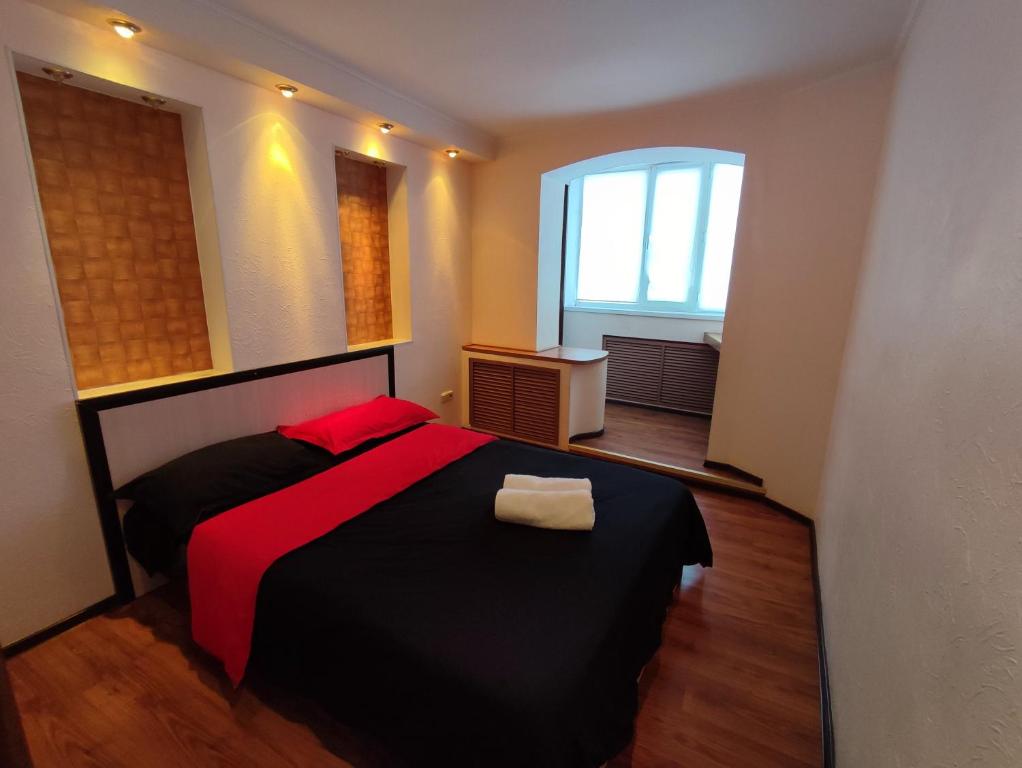 巴甫洛达尔Уютная трёхкомнатная квартира的一间卧室配有一张黑色床、红色床单和窗户。