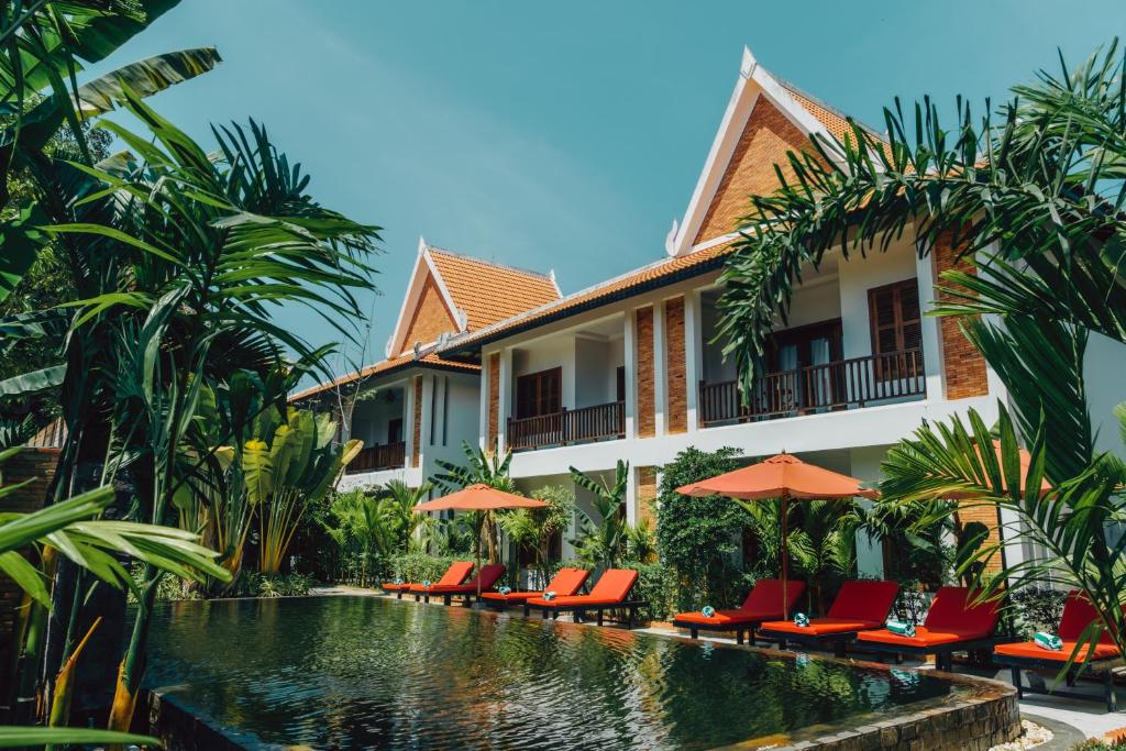 暹粒Bopha Wat Bo Residence的一个带椅子和遮阳伞的游泳池的度假酒店