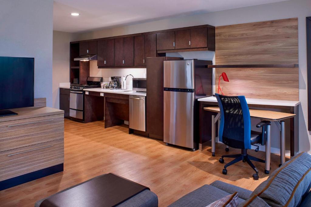 里士满TownePlace Suites by Marriott Richmond的厨房配有书桌、冰箱和桌子