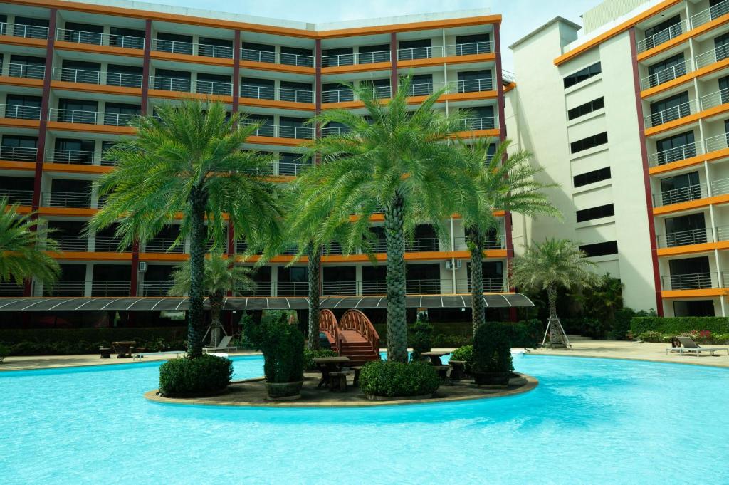 迈考海滩777 Beach Condo Phuket的一座楼前种有棕榈树的游泳池