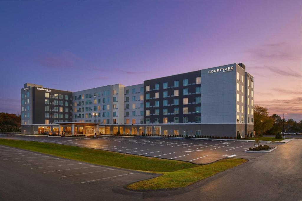 奥尔巴尼Courtyard by Marriott Albany Airport的一座大型建筑,前面设有停车场