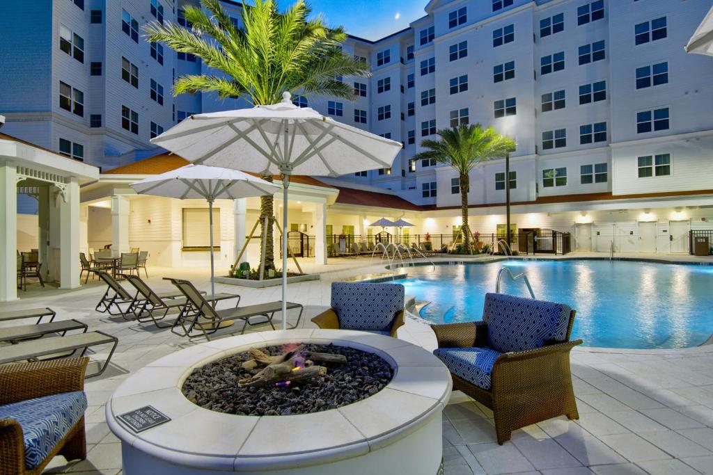 奥兰多Residence Inn by Marriott Orlando at FLAMINGO CROSSINGS Town Center的酒店设有一个游泳池和一个带火坑的庭院