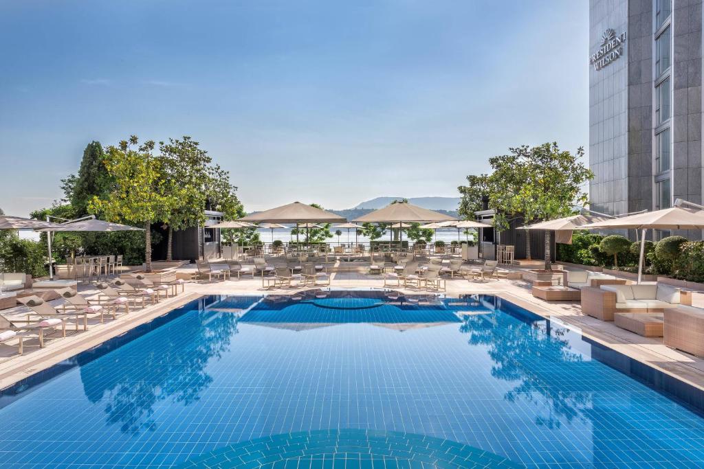 日内瓦Hotel President Wilson, a Luxury Collection Hotel, Geneva的一个带椅子和遮阳伞的游泳池