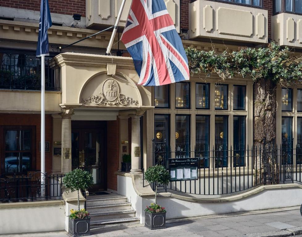 伦敦The Capital Hotel, Apartments & Townhouse的建筑物前悬挂的英国国旗