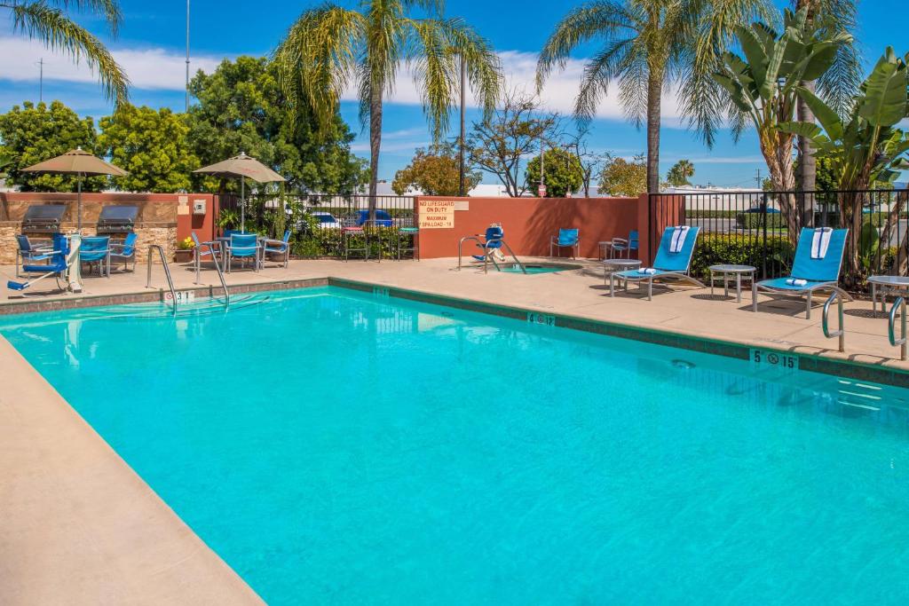 安纳海姆阿纳海姆天使球场万豪广场套房酒店的一个带蓝色椅子和棕榈树的大型游泳池