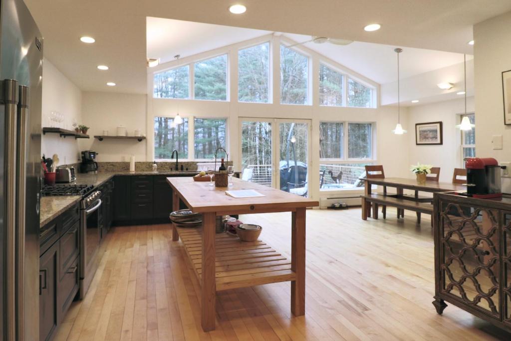 大巴灵顿Woodland Hills Modern Cottage Minutes from Downtown Great Barrington的厨房配有木桌和大窗户。