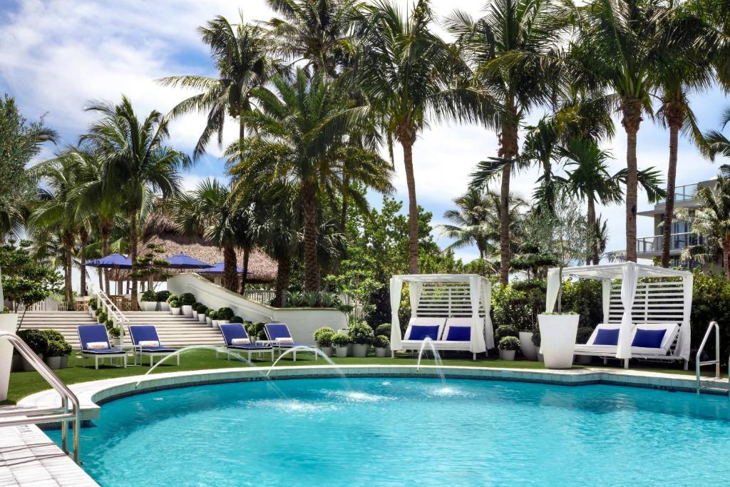 迈阿密海滩凯迪拉克签名系列酒店及海滩俱乐部的一个带椅子的游泳池,棕榈树