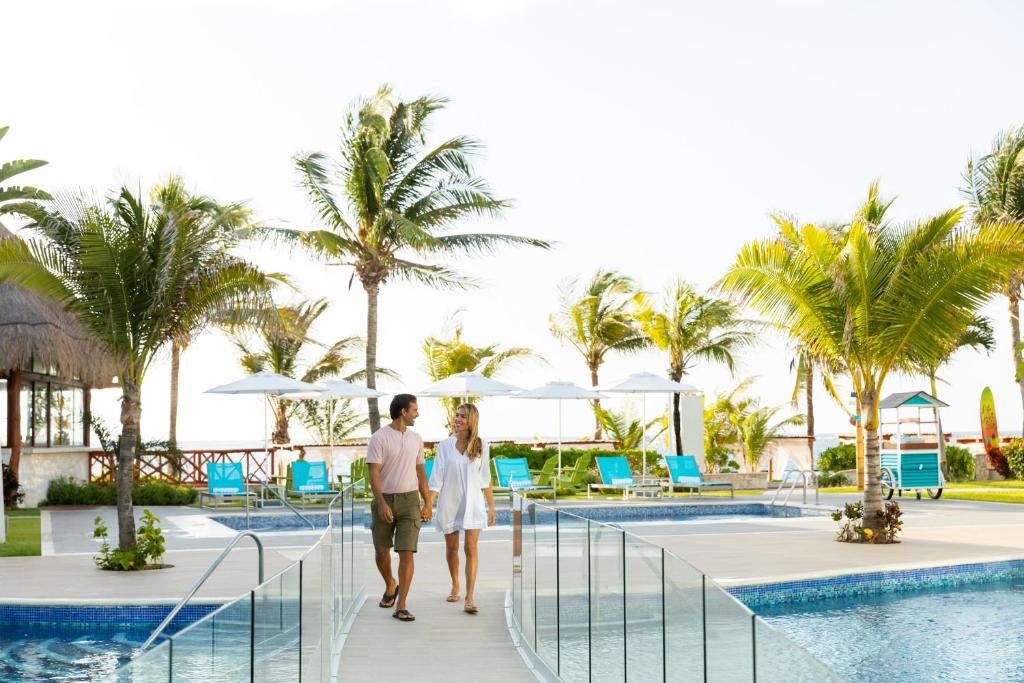 莫雷洛斯港Margaritaville Island Reserve Riviera Cancún - An All-Inclusive Experience for All的男人和女人在度假村的泳池边走