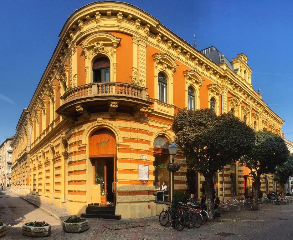 佩奇NAPartman Pécs的街道上一座大型黄色建筑,设有阳台