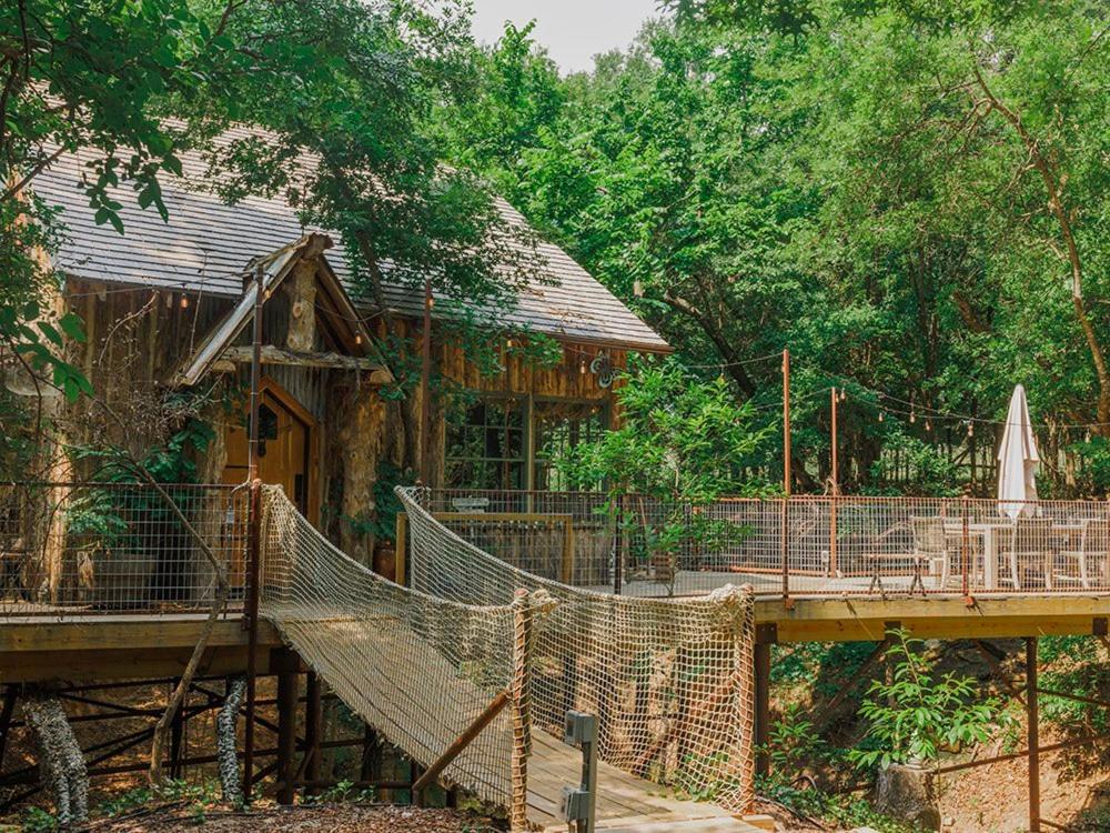 韦瑟福德Hobbit Treehouse with waterfall on the Brazos River! 350 acres! Tubing! Petting zoo!的一座带桥的房子前面的吊床