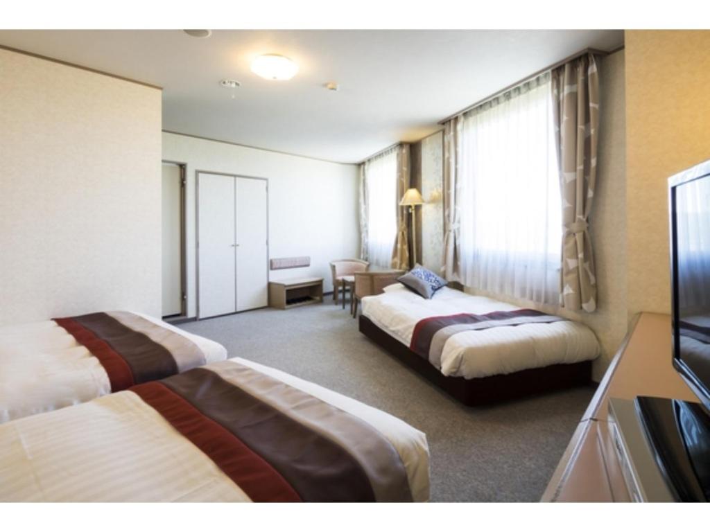 东广岛市Hotel Areaone Hiroshima Wing - Vacation STAY 62261v的酒店客房设有两张床和电视。