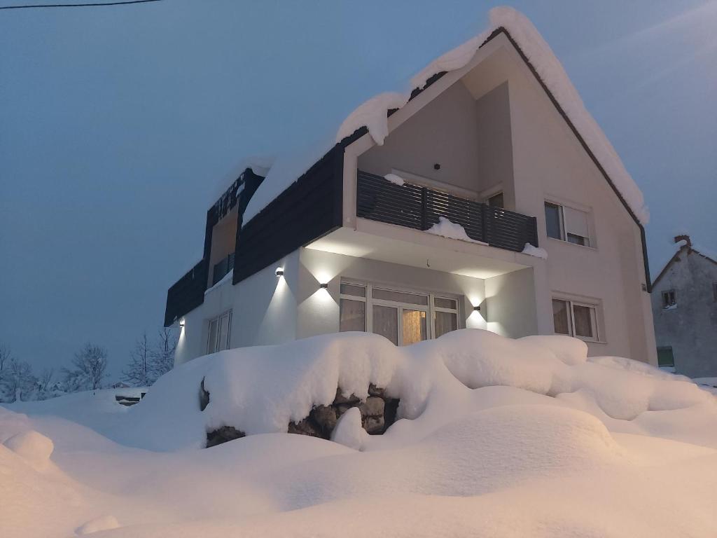 戈斯皮奇Elegant Inn Gospić的前面的雪覆盖的房子