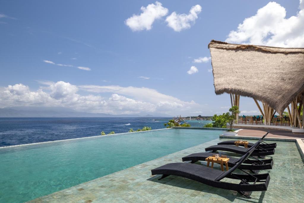 珀尼达岛Pramana Natura Nusa Penida的一个带躺椅的游泳池和海洋