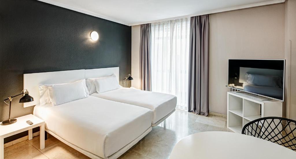 马德里Sercotel Togumar的卧室配有一张白色大床和电视。