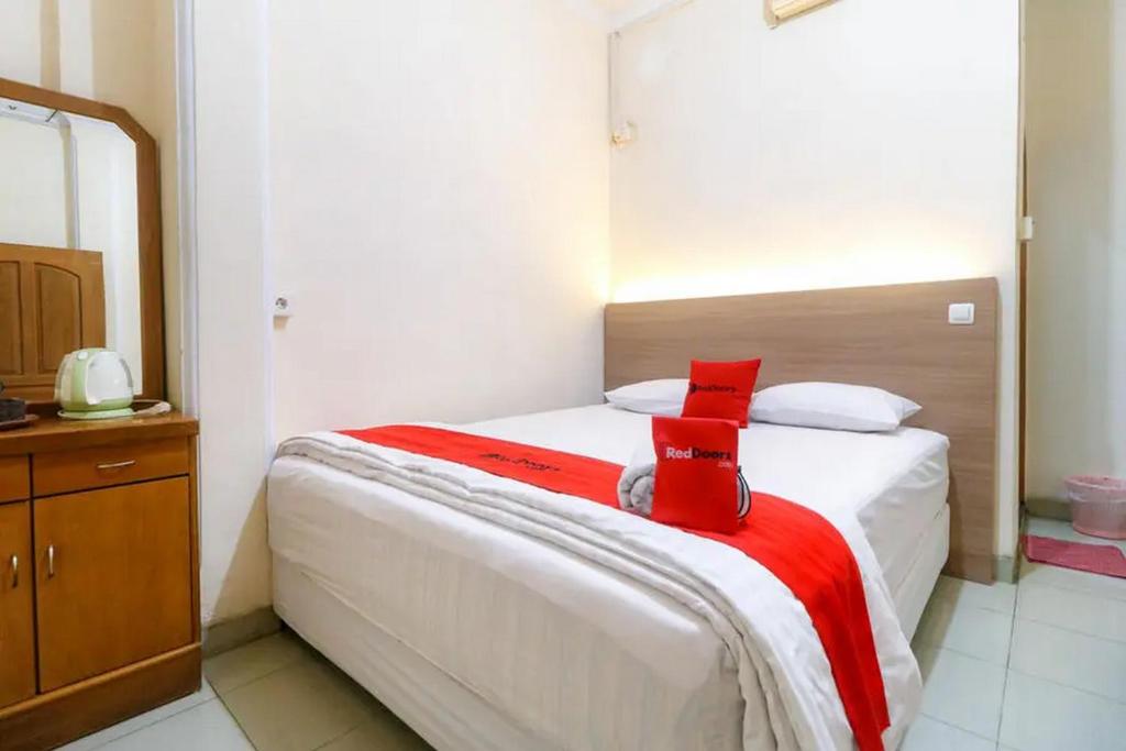 TanjungjohorRedDoorz Plus near WTC Batanghari Mall的一间卧室配有一张床铺,床上铺有红色毯子