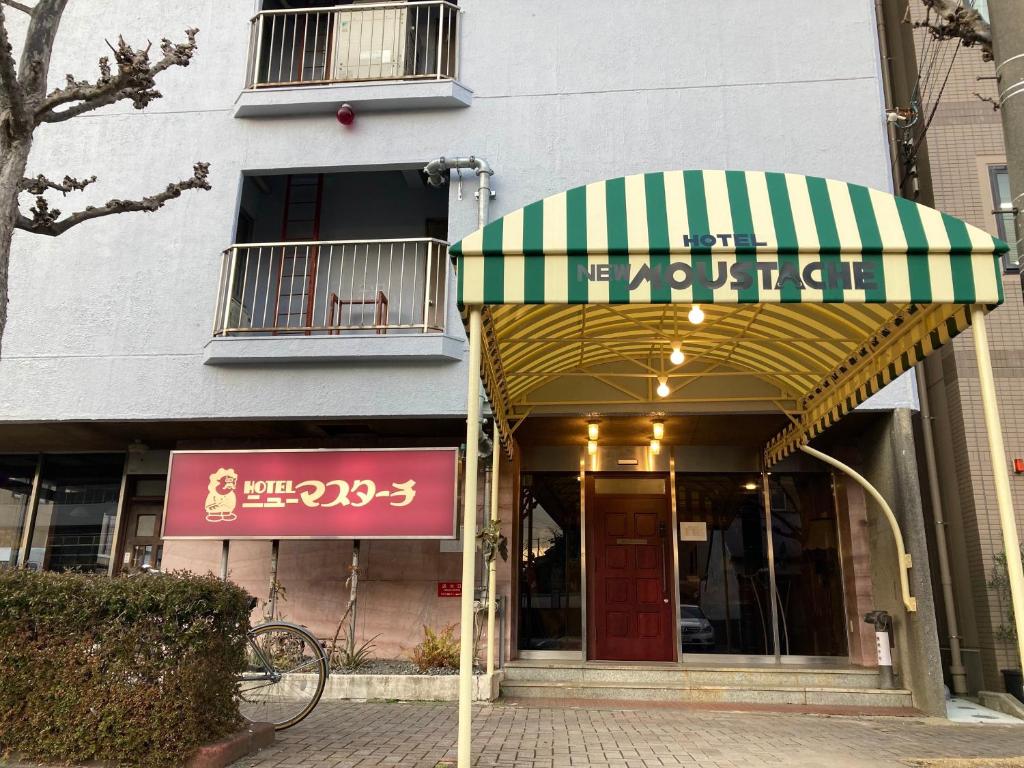 静冈Hotel New Moustache的绿色和白色遮阳篷的商店前