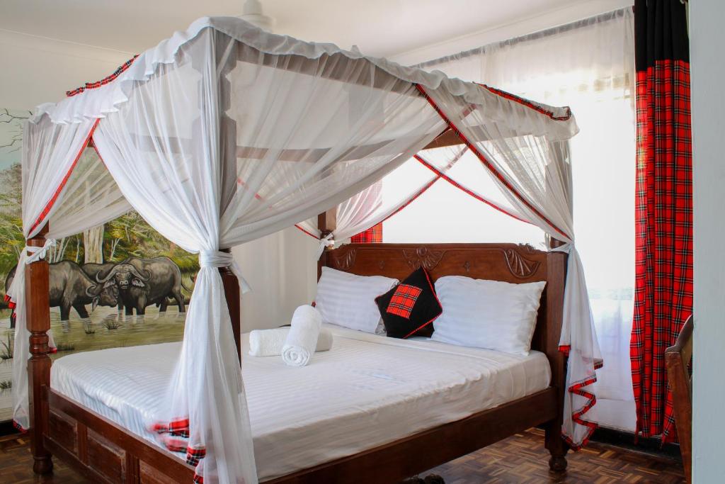 蒙巴萨Maasai Villas的一间卧室配有一张带马篷的床铺,背面是马。