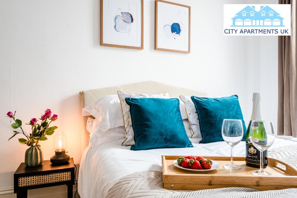 伦敦Charming 1 Bed Apt in Kensington - Free London Tour Included By City Apartments UK Short Lets Serviced Accommodation的一张带水果和酒杯托盘的床