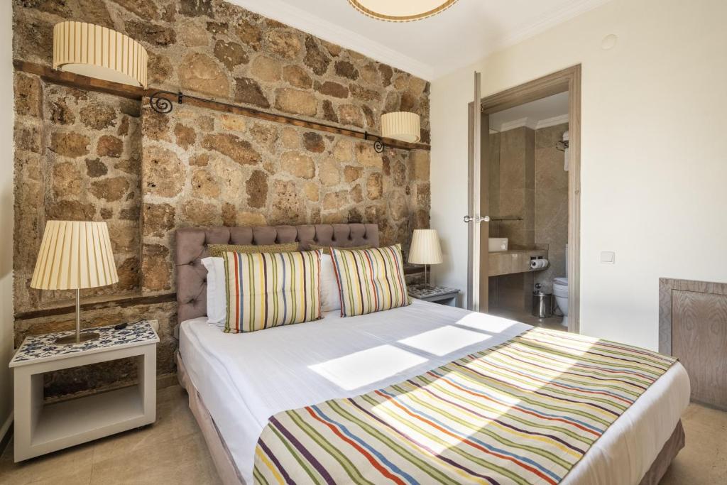 安塔利亚Glamorous Flat with Jacuzzi near Hadrians Gate的一间卧室设有一张床和石墙