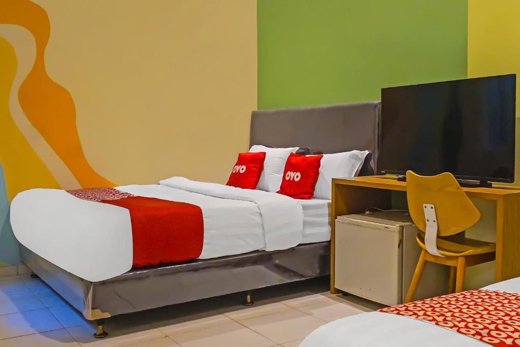 当格浪SUPER OYO 92271 Orienchi 3的一间卧室配有一张带红色枕头的床和一台电视。
